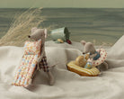 Two toy mice on a sandy beach with beach accessories