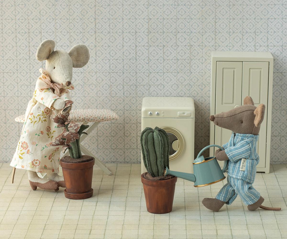 Two toy mice in a room with a washing machine and potted plants.