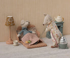 Two toy animals, a bear and a fox, in a cozy room setting with a lamp, table, and chair.
