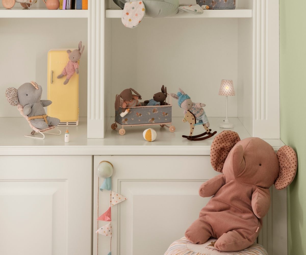 Children's toys including a plush elephant, rocking horse, and other items on a shelf.