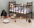 Children's room with wooden crib, toys, and books on a light wood floor.