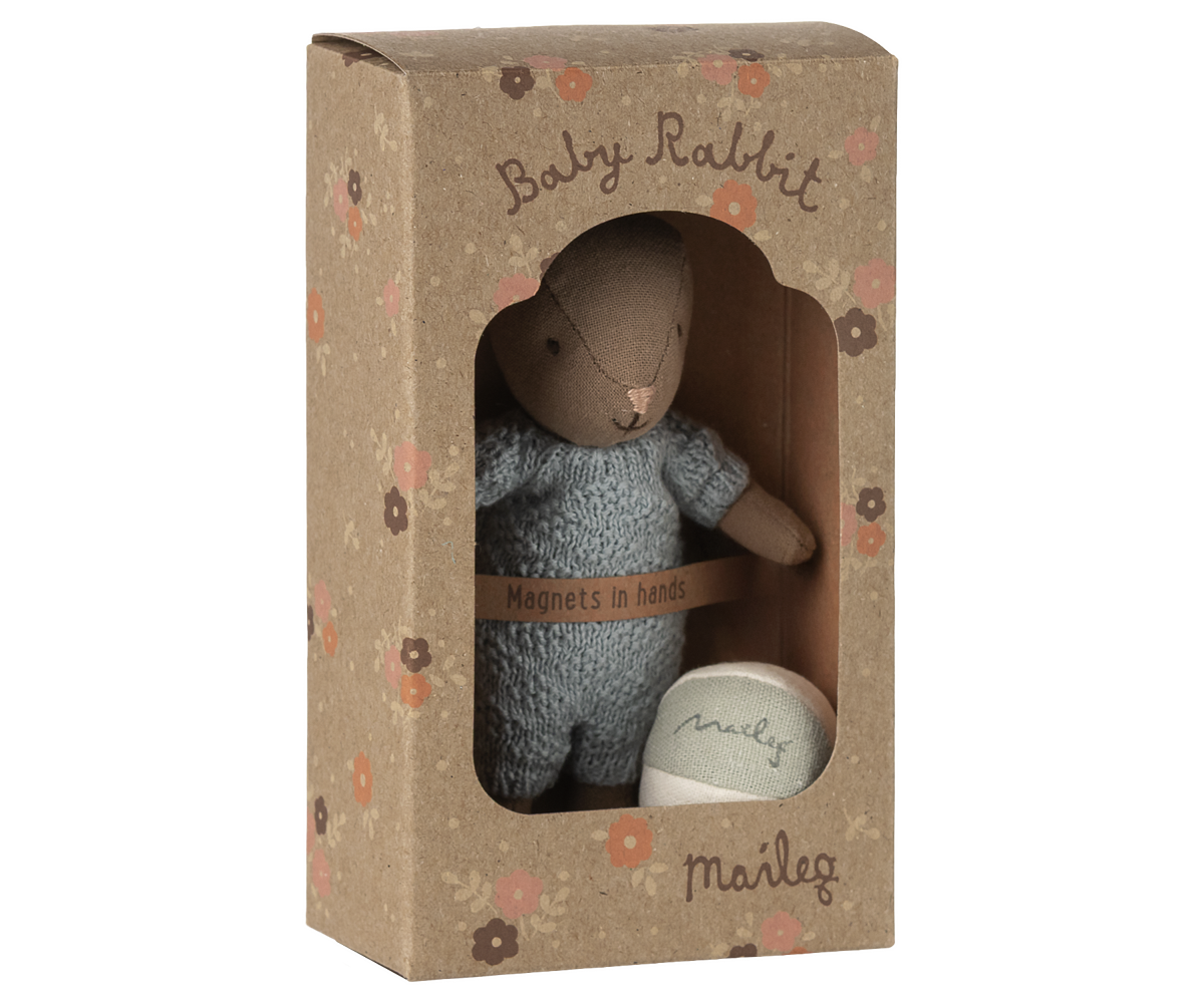 Stuffed toy rabbit in a cardboard box with 'Baby Rabbit' text on a white background