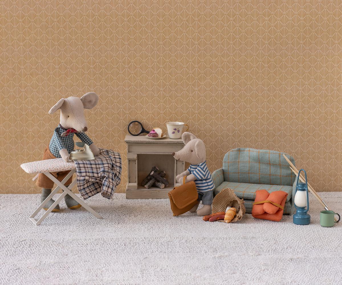 Two toy mice in a living room setting with furniture and accessories on a beige patterned wall background.