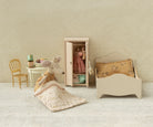 Miniature bedroom set with bed, wardrobe, chair, and mouse figure on a textured surface.