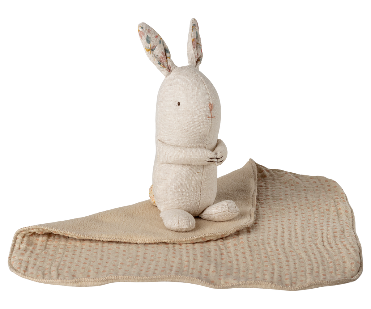 Stuffed rabbit toy with a beige blanket on a white background