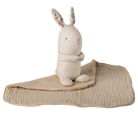 Stuffed rabbit toy with a beige blanket on a white background