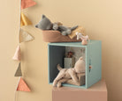 Children's room with a teal cube, plush toys, and decorative pillows on a beige wall.