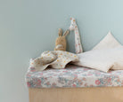 Children's bed with floral bedding, plush toys, and a light blue wall.