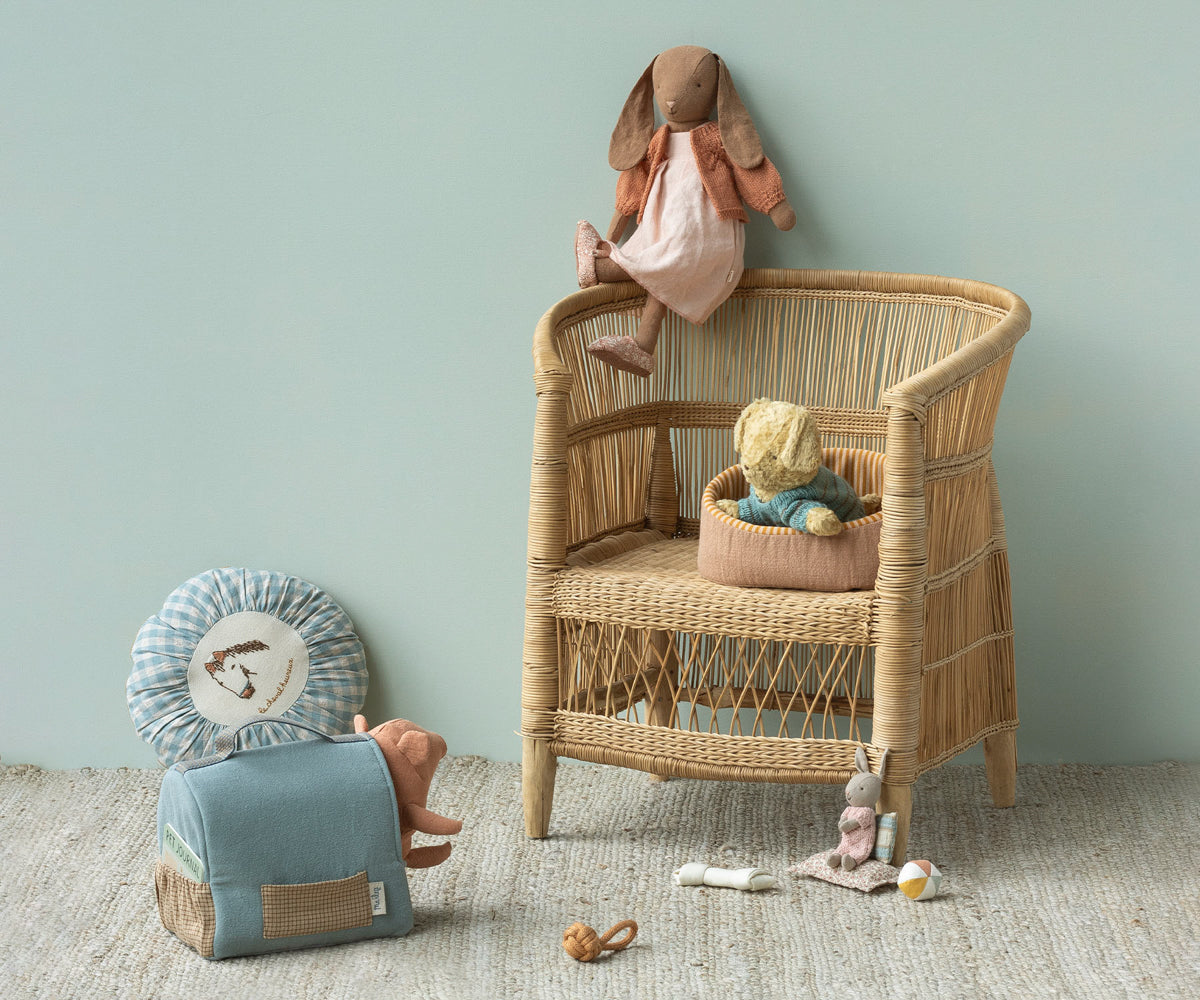 Wicker chair with toys against a light green wall