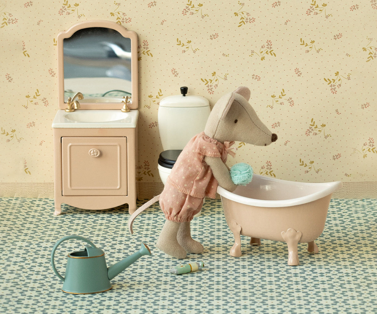 Toy mouse in a bathtub with bathroom furniture and decor in the background