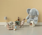 Children's playroom with stuffed toys including a large gray elephant, rabbit, and bear on a beige floor and wall.