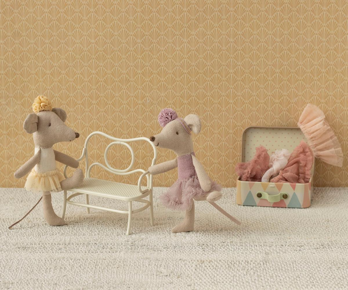 Two toy mice with a chair and box on a textured surface with patterned wall background