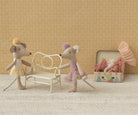 Two toy mice with a chair and box on a textured surface with patterned wall background