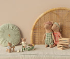 Children's toys including teddy bears and a wooden crate on a beige surface with a wicker chair and decorative items in the background.