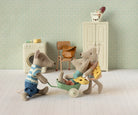 Toy mice in a miniature room with a washing machine and chair.