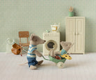 Two toy mice in a miniature room with a washing machine and furniture.