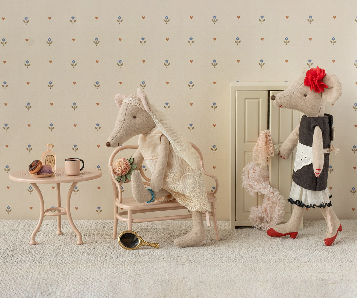 Two plush mice in a decorative room with wallpaper and furniture.