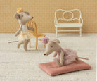 Two plush mouse toys in decorative outfits on a textured surface with chairs in the background.