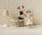 Two toy mice in a room with a lamp, table, and mirror.