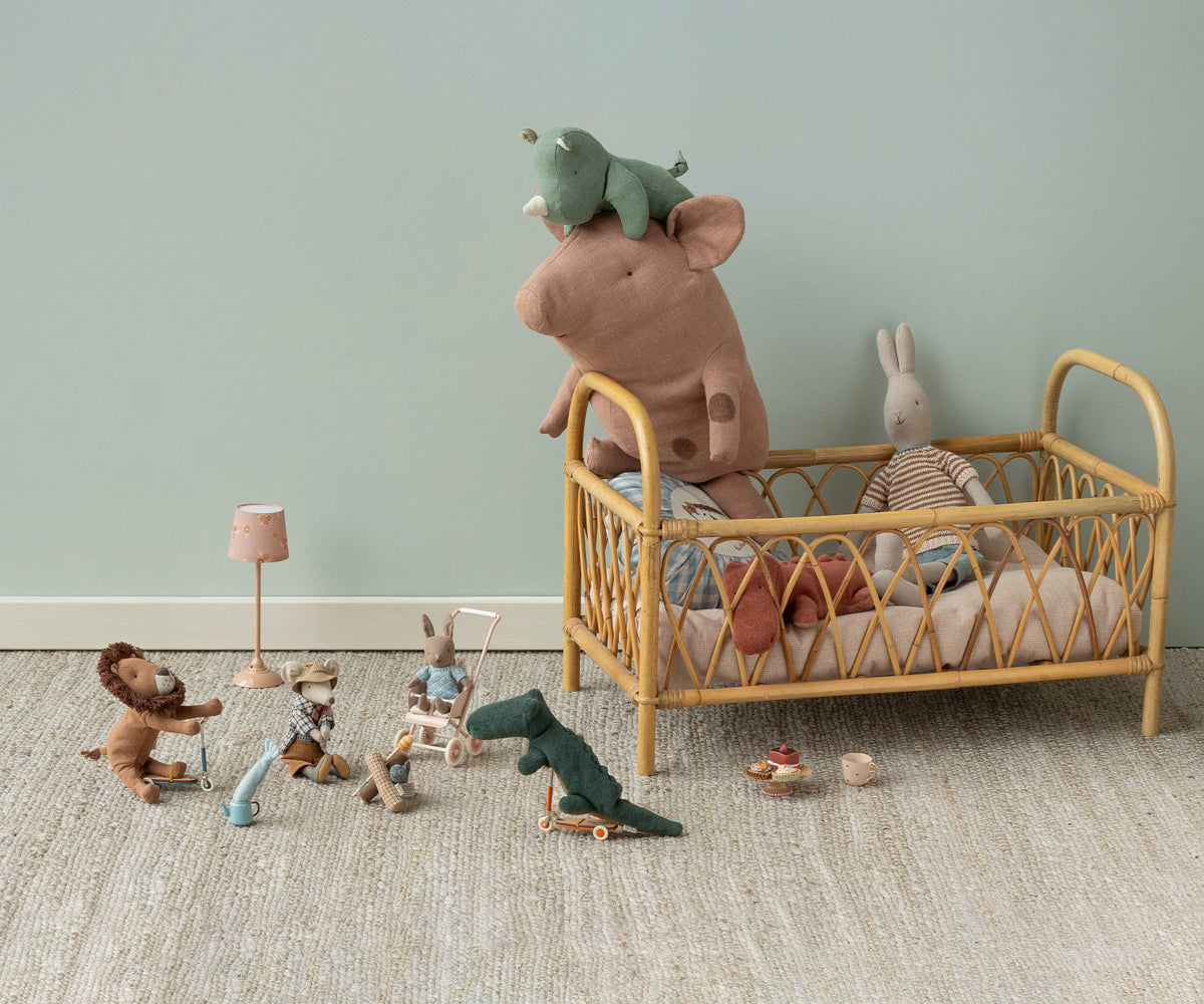 Children's room with a wooden crib, plush toys, and small figurines on a light green wall background.