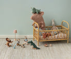 Children's room with a wooden crib, plush toys, and small figurines on a light green wall background.