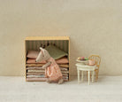 A Maileg toy set featuring a Big Sister mouse standing next to a wooden bed frame piled high with colorful layered mattresses, with a miniature table and chair set nearby holding tiny treats and a teapot.