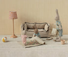 Children's room with toy sofa, rabbit figure, and lamp against a beige wall.