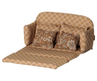 A miniature ocher fabric sofa bed pulled out into a bed for a toy mouse house, featuring a retro floral pattern in shades of brown and cream, with matching back cushions and side pillows against a transparent background.