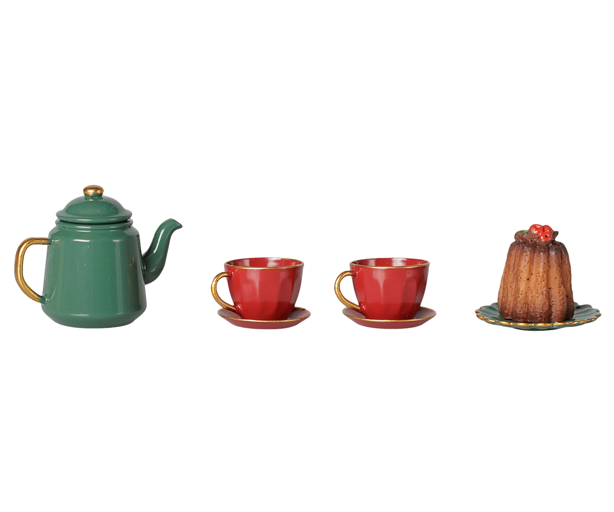 A green metal teapot, two red teacups and saucers, and a miniature cake on a decorative plate, displayed on a transparent background.
