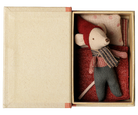 A small plush mouse toy dressed in a red hat and scarf with gray pants, displayed inside an open beige gift box with a red patterned pillow.