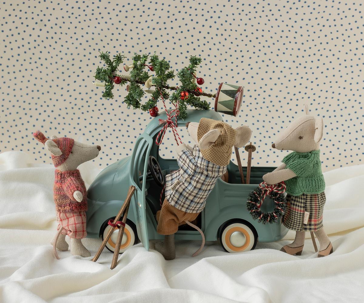 Several Maileg mouse toys gathered around a vintage-style mint-green toy car on a soft, draped white fabric background.