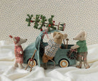 Several Maileg mouse toys gathered around a vintage-style mint-green toy car on a soft, draped white fabric background.