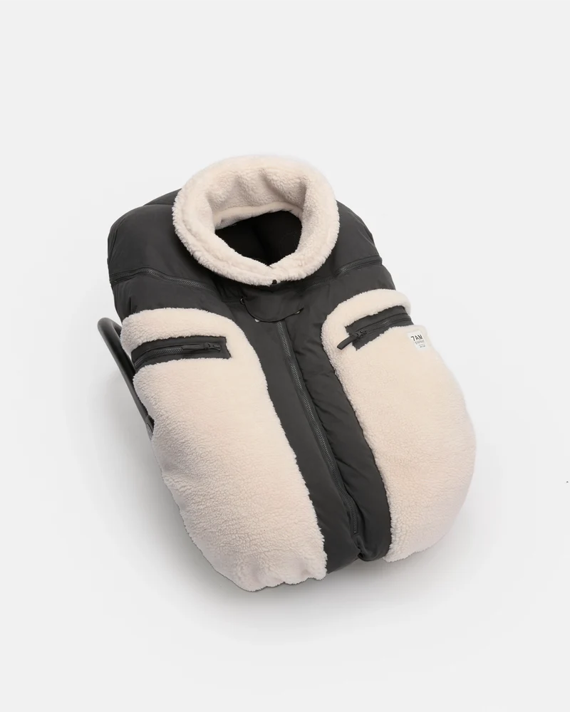 A baby footmuff in black and cream fleece, shown on a clean white background.