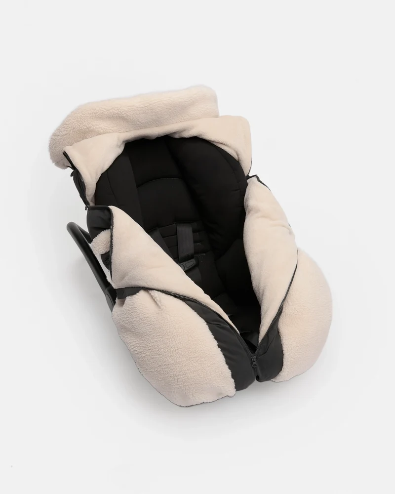 A beige fleece-lined car seat cover with black trim and a black interior padding, shown from an overhead angle on a light gray background.