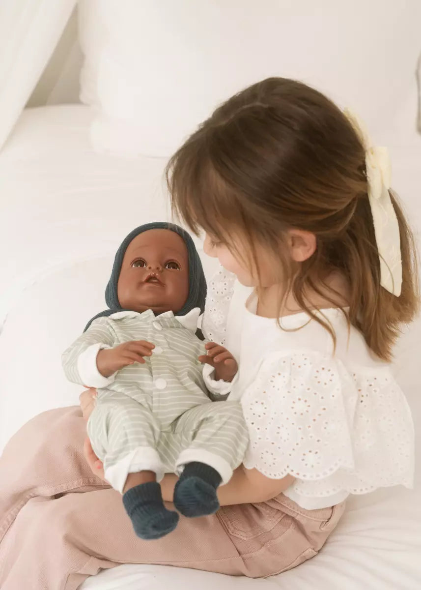 Child holding a baby doll with a neutral background