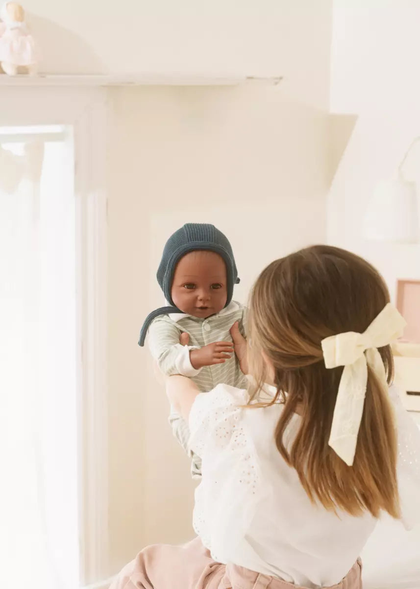 Woman holding a baby in a room with white walls and a lamp.