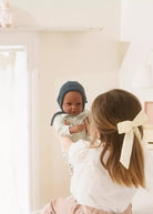 Woman holding a baby in a room with white walls and a lamp.