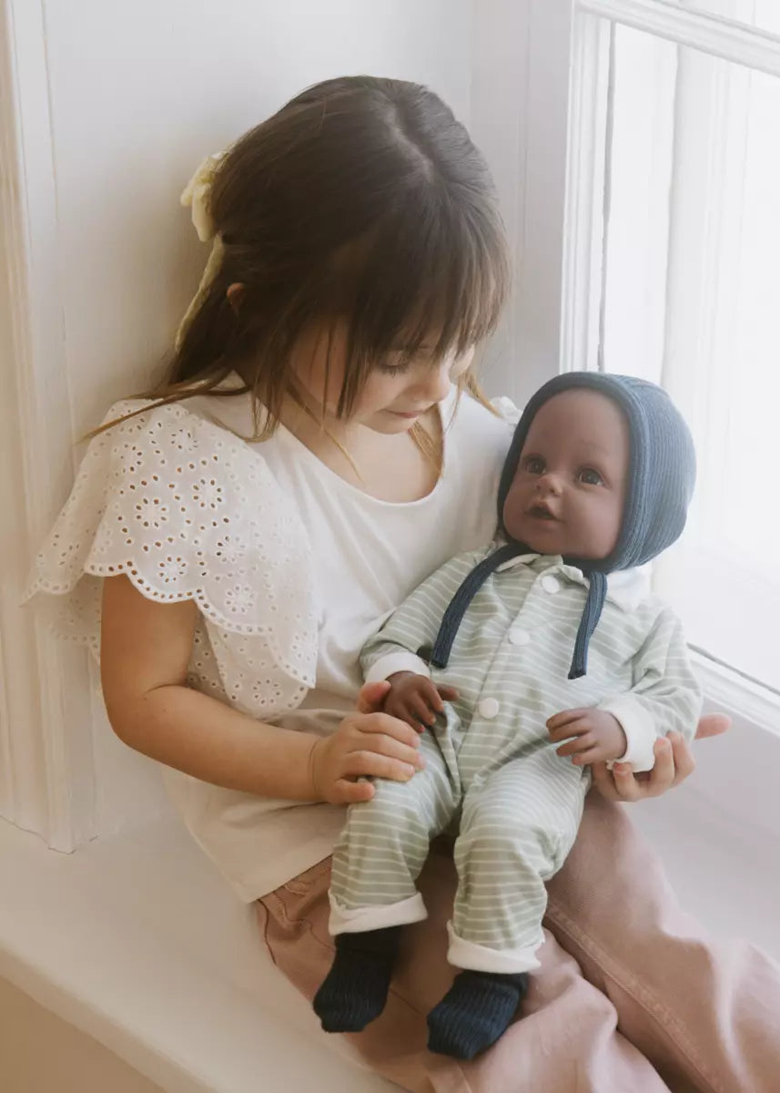Child holding a baby in a room with a window