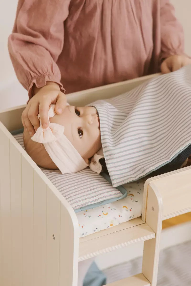Person attending to a baby in a crib with a striped blanket