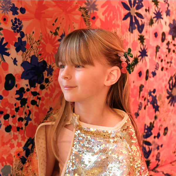 Young girl with floral hair accessories against a colorful floral-patterned background