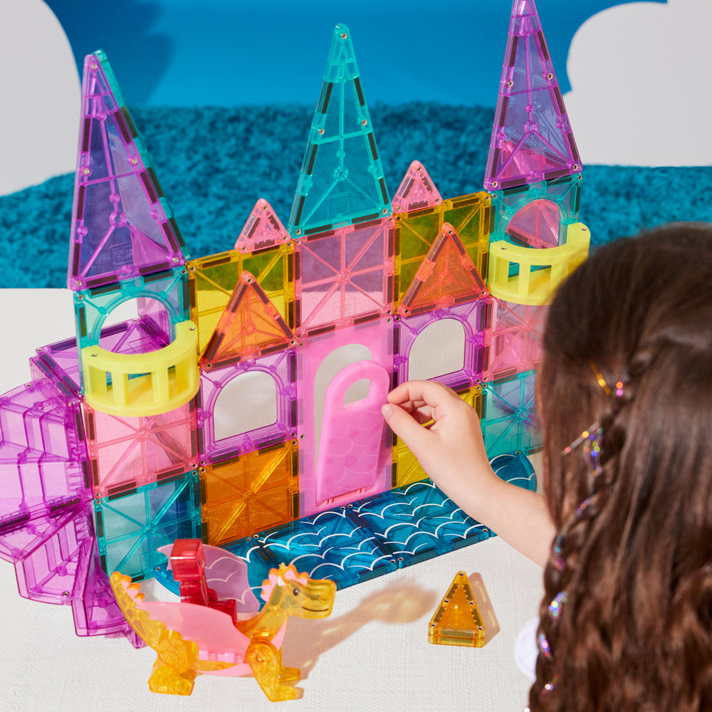Colorful magnetic building blocks being used to construct a castle with a child's hand visible.