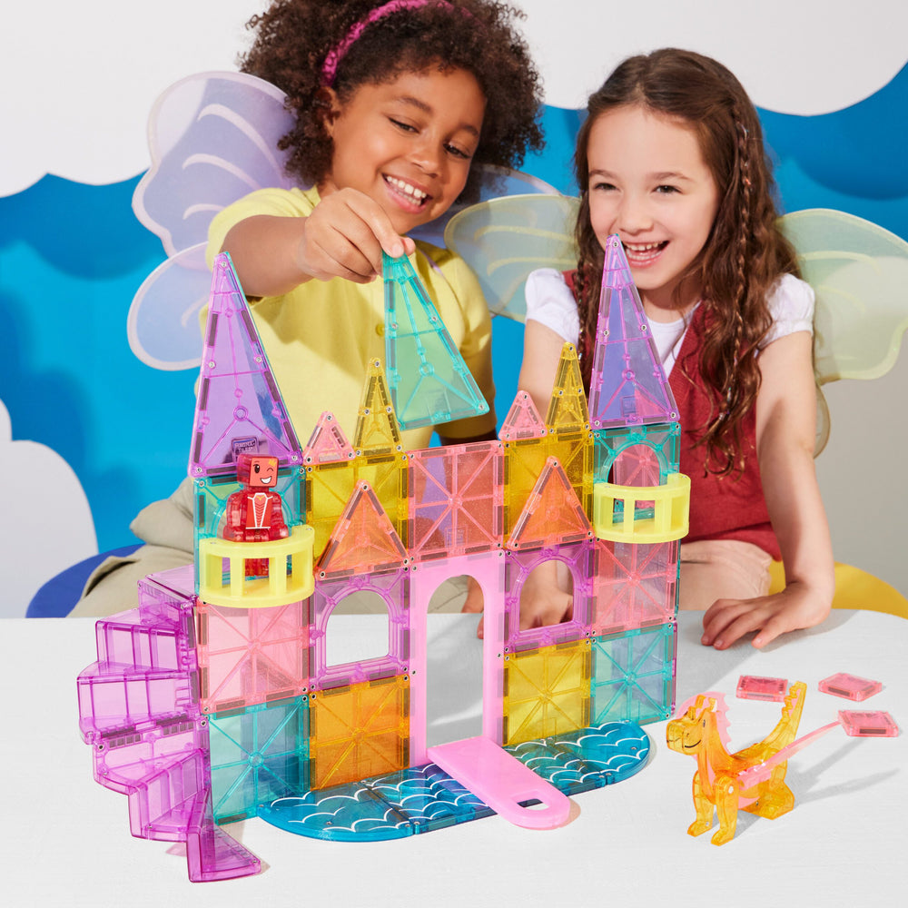 Two children playing with colorful magnetic building blocks on a white surface.
