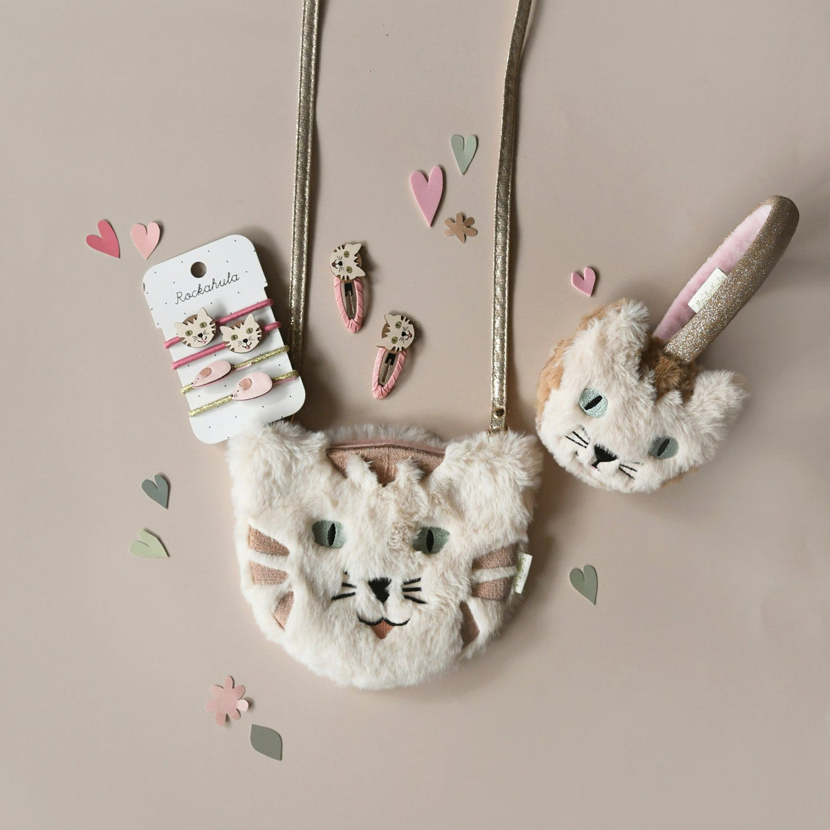 Children's bag with cat design, rabbit ears, and hair accessories on a beige background