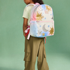 A child wearing a pastel rainbow backpack with gold sun and moon prints, shown from the back against a solid mint green background.