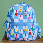 Blue checkered backpack with colorful charms on a green background