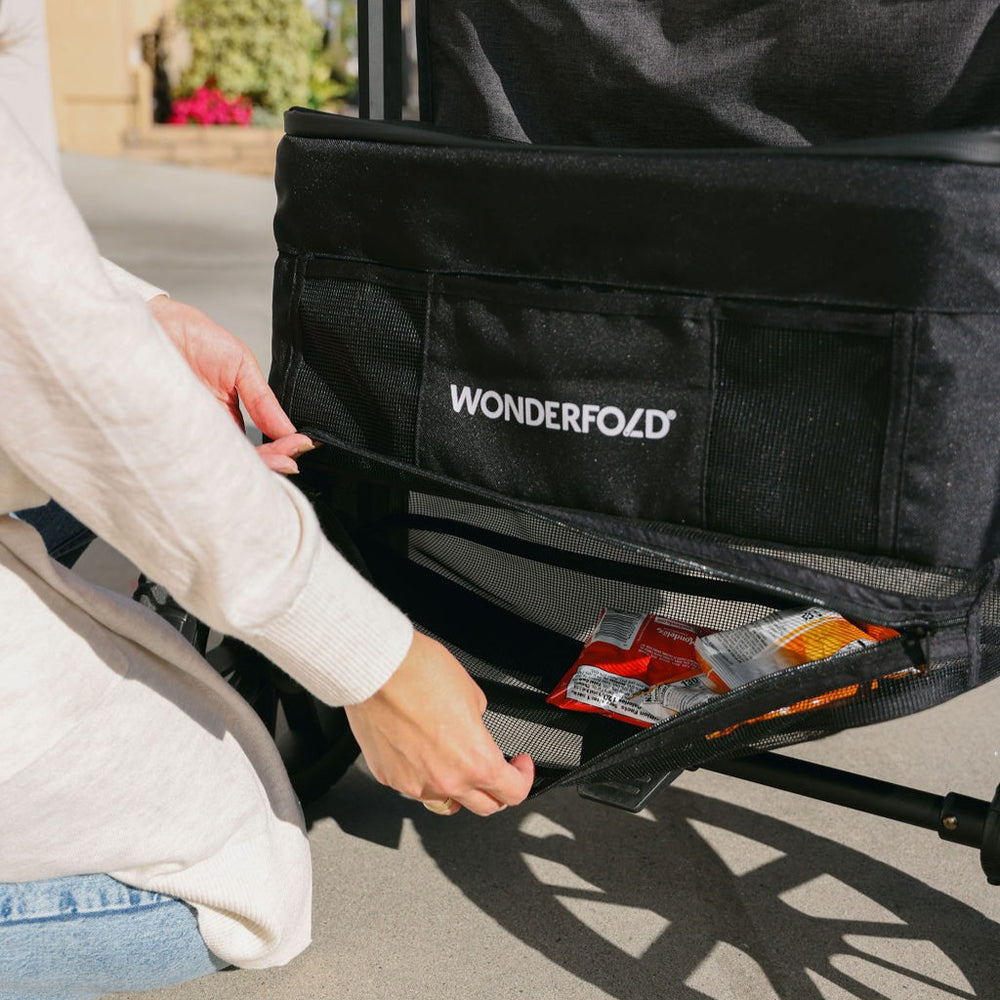 Person opening a black WonderFold stroller bag with snacks visible.