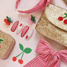 Gold glittery pouches with cherry designs on a light pink background