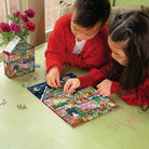 Two children playing with a puzzle on the floor next to a box of puzzles.