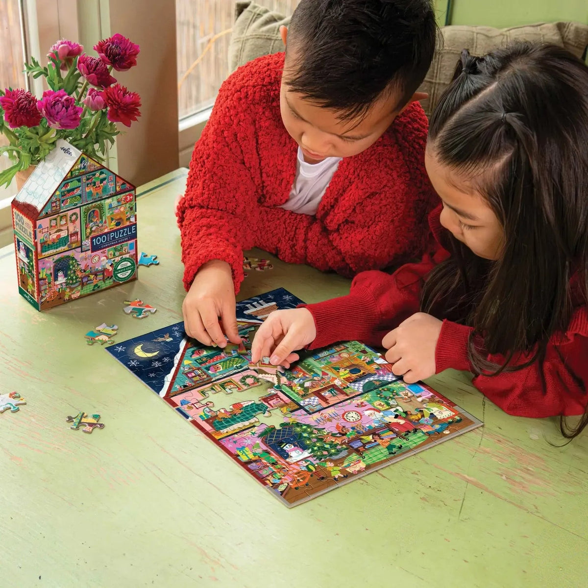 Two children playing with a puzzle on the floor next to a box of puzzles.