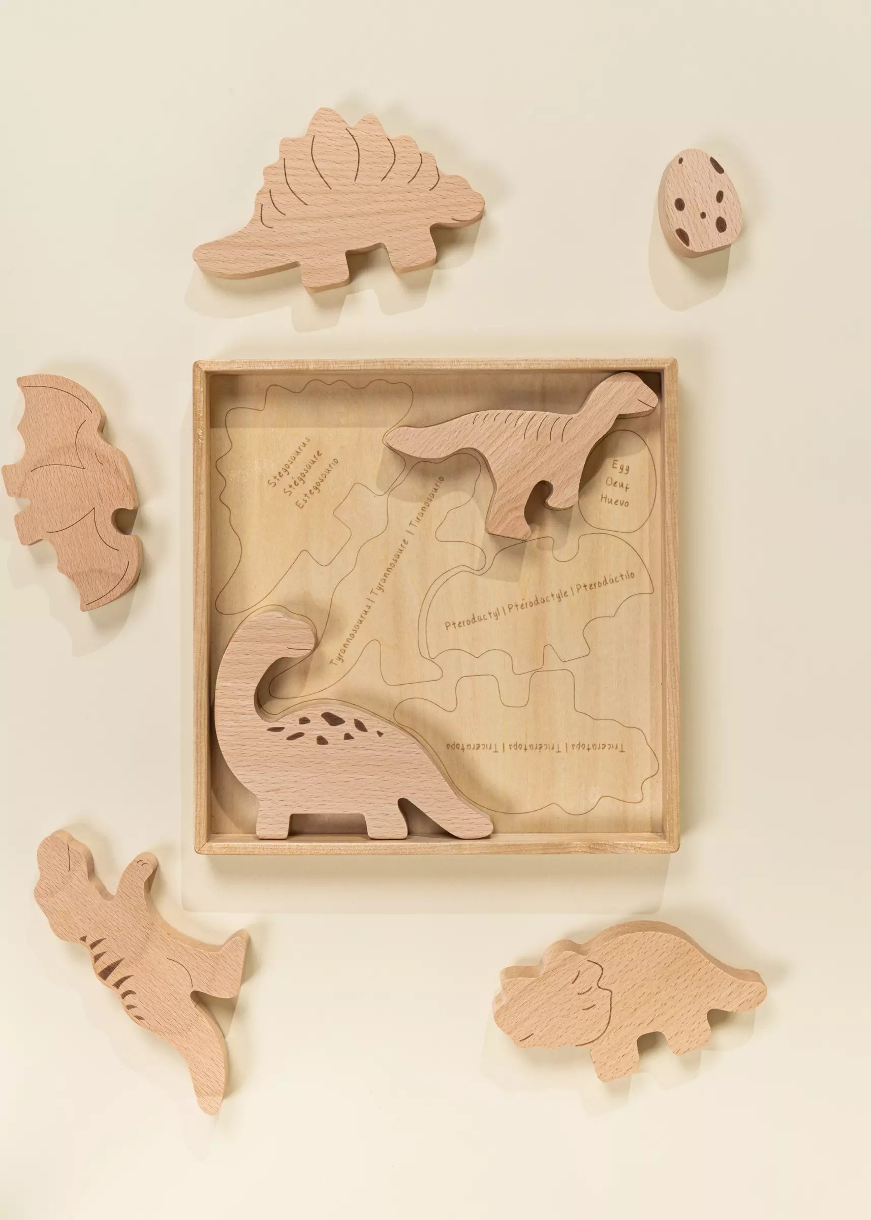 Wooden dinosaur puzzle with pieces displayed on a beige background